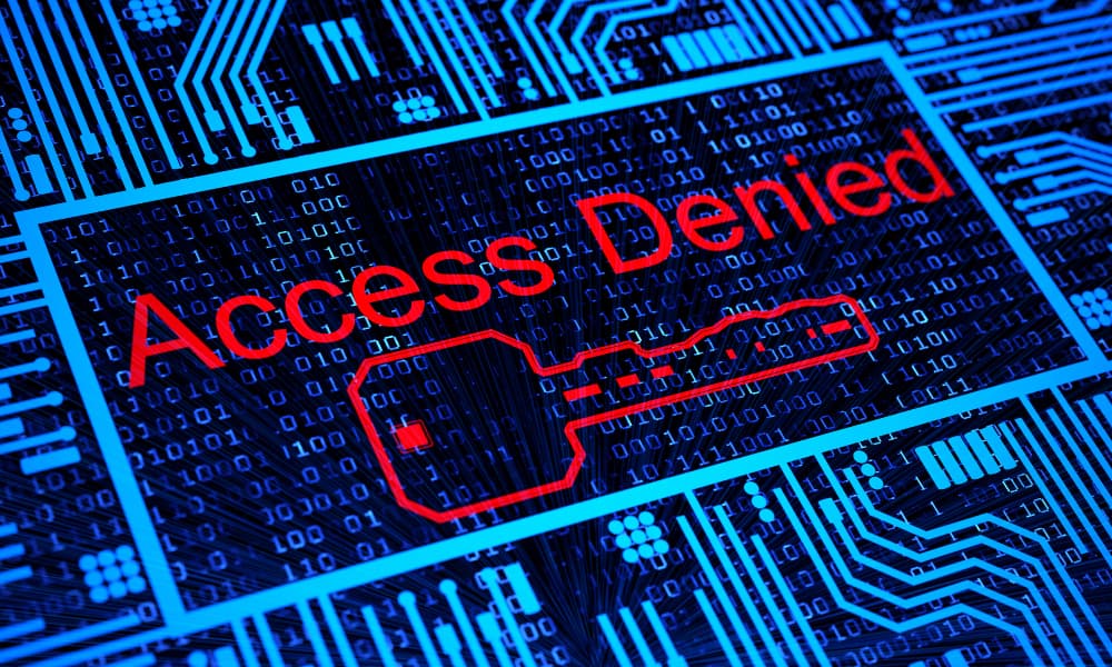 A computer screen in which the words "Access Denied" in red letters over a detailed blue circuit board background, with a key symbol underneath the text.